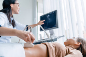 Female doctor using ultrasound scanner on a woman's abdomen to diagnose fibroids